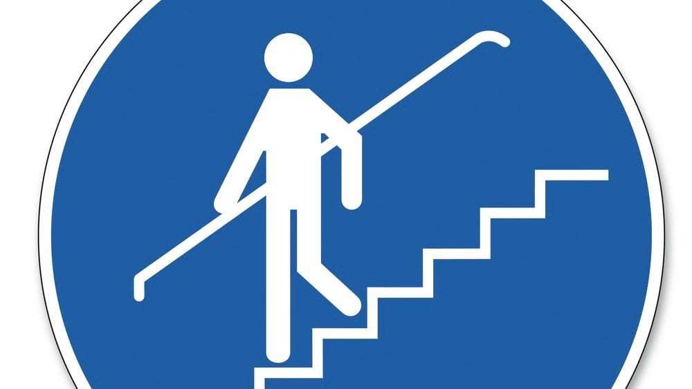 safety sign showing person walking down stairs holding handrail