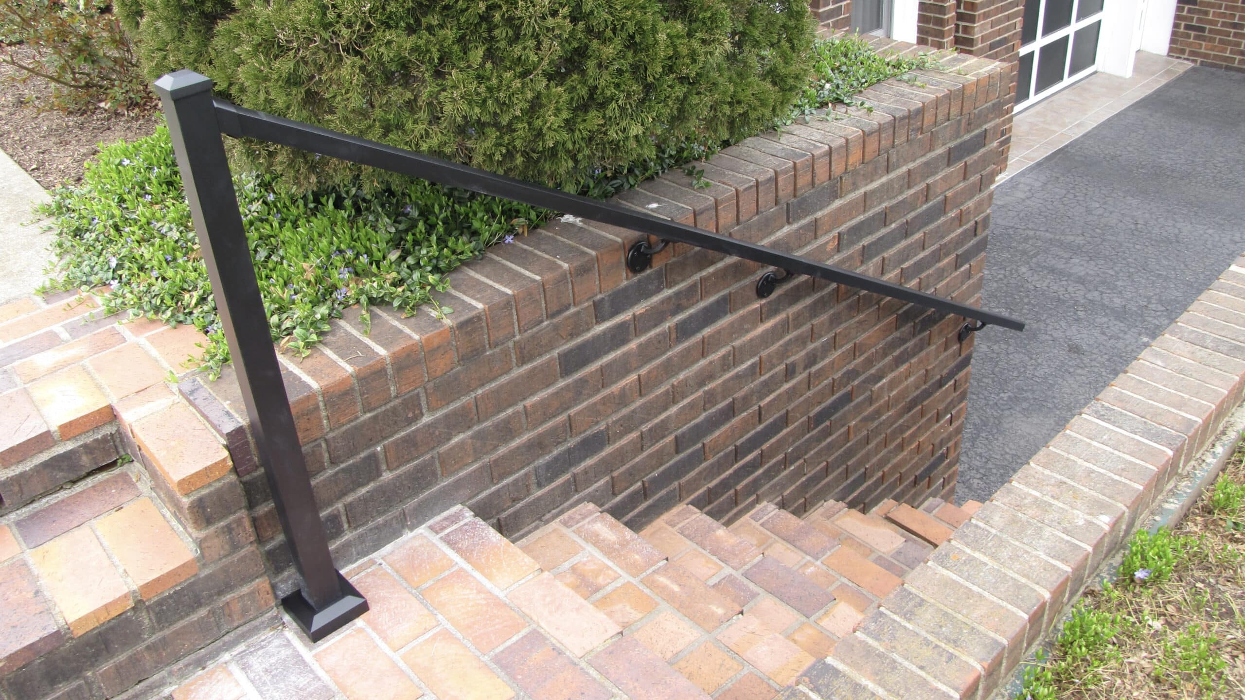 Downward view of brick steps with aluminum handrail on one side
