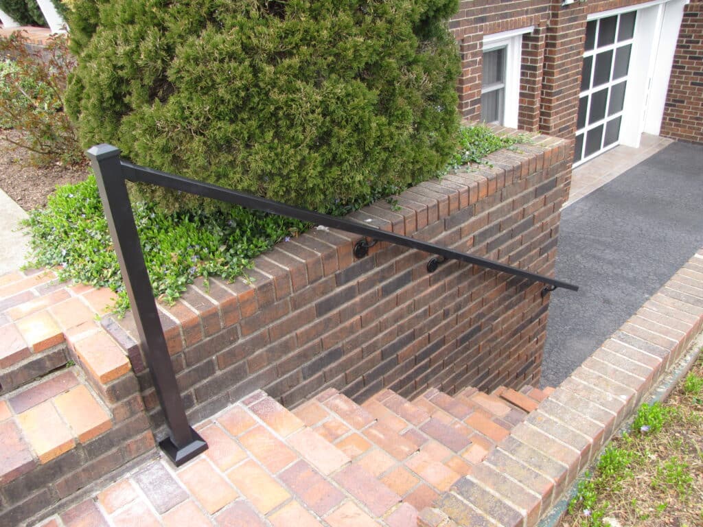 Downward view of brick steps with aluminum handrail on one side