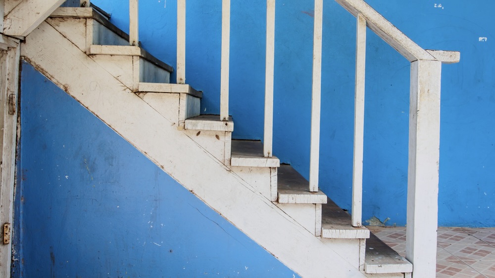 Old white handrail against blue wall