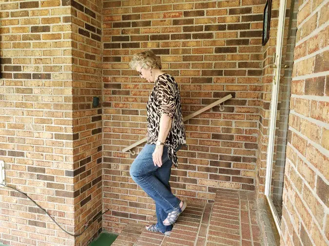 woman holding on to a handrail while walking down brick steps